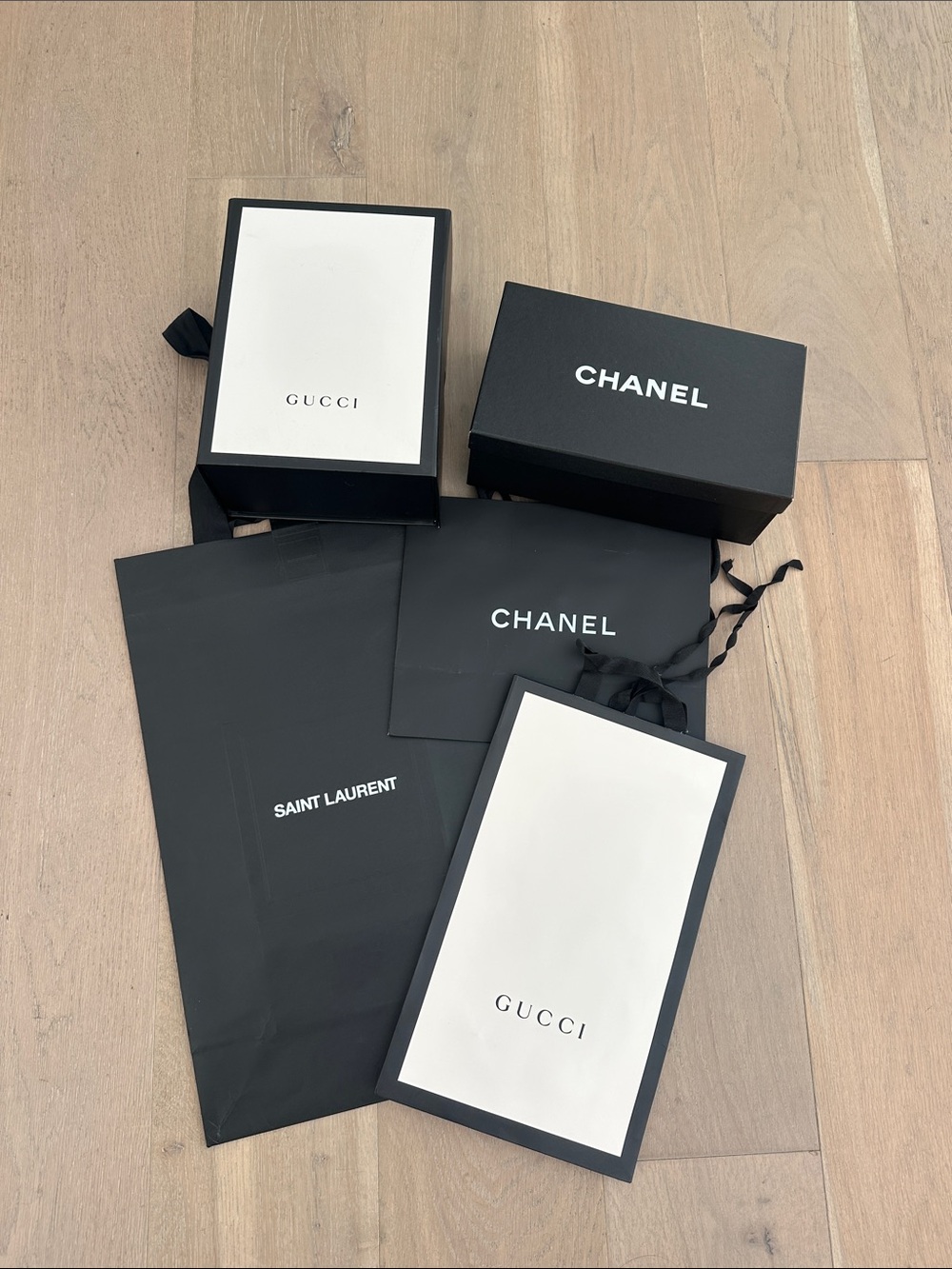Assortment of Chanel, Saint Laurent and Gucci shopping bags and boxes